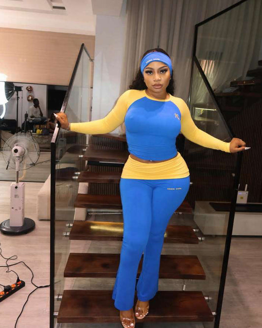Woman in blue and yellow outfit standing in a room with glass walls.