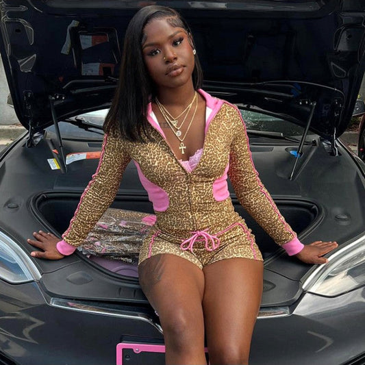 Woman in a gold and pink outfit sitting in the open trunk of a car.